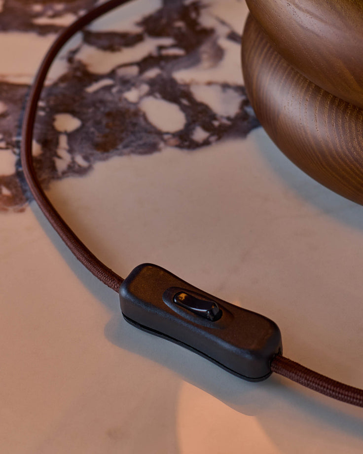 Dark wood table lamp with linen shade and fabric cord detail, showing close-up of power switch on cord.