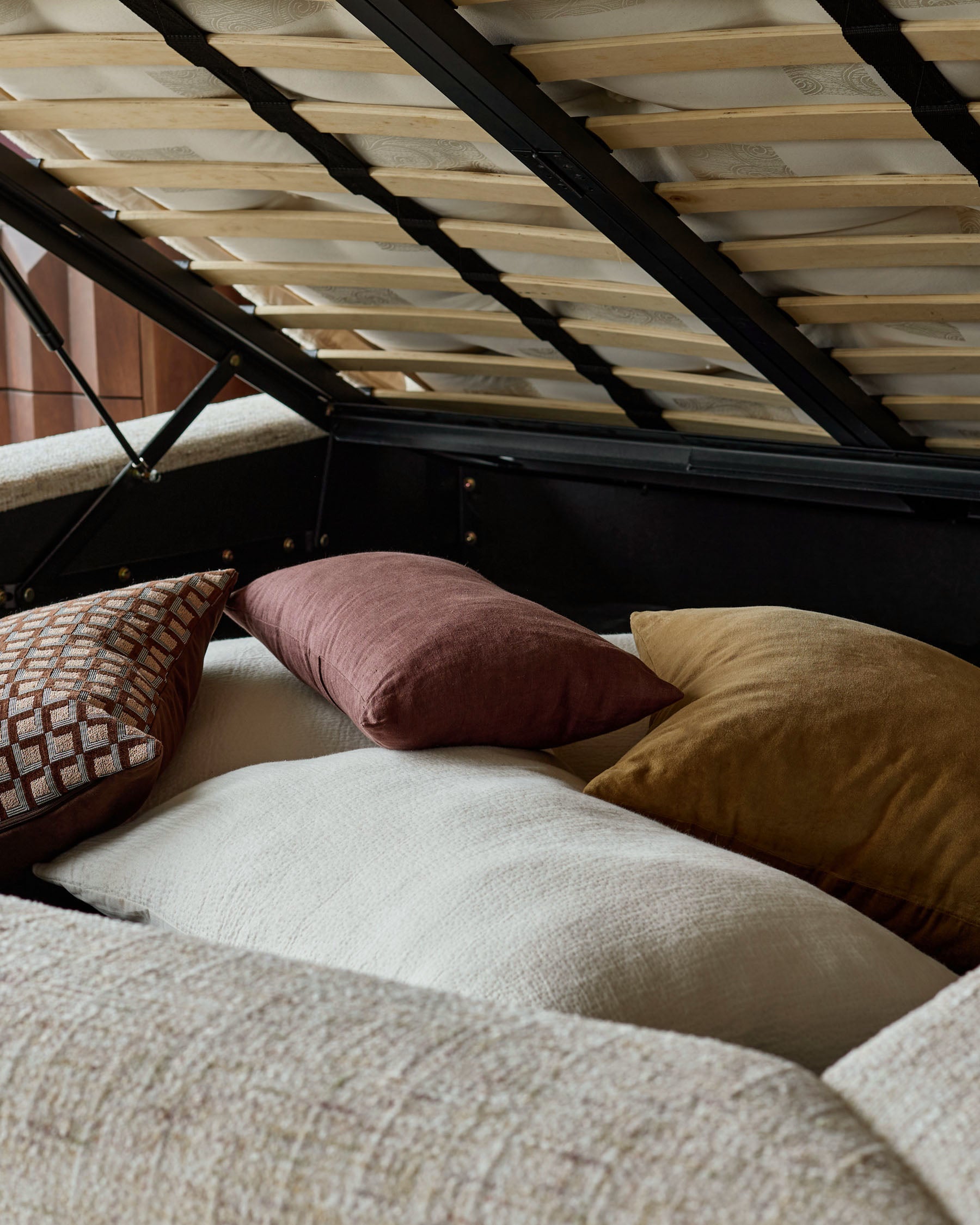 Hepworth King-Size Ottoman Bed in natural fabric with open storage base, styled with decorative pillows and wooden slat headboard.
