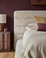 Hepworth king-size ottoman bed with natural linen upholstery, displayed in bedroom setting with neutral bedding and burgundy accent wall.