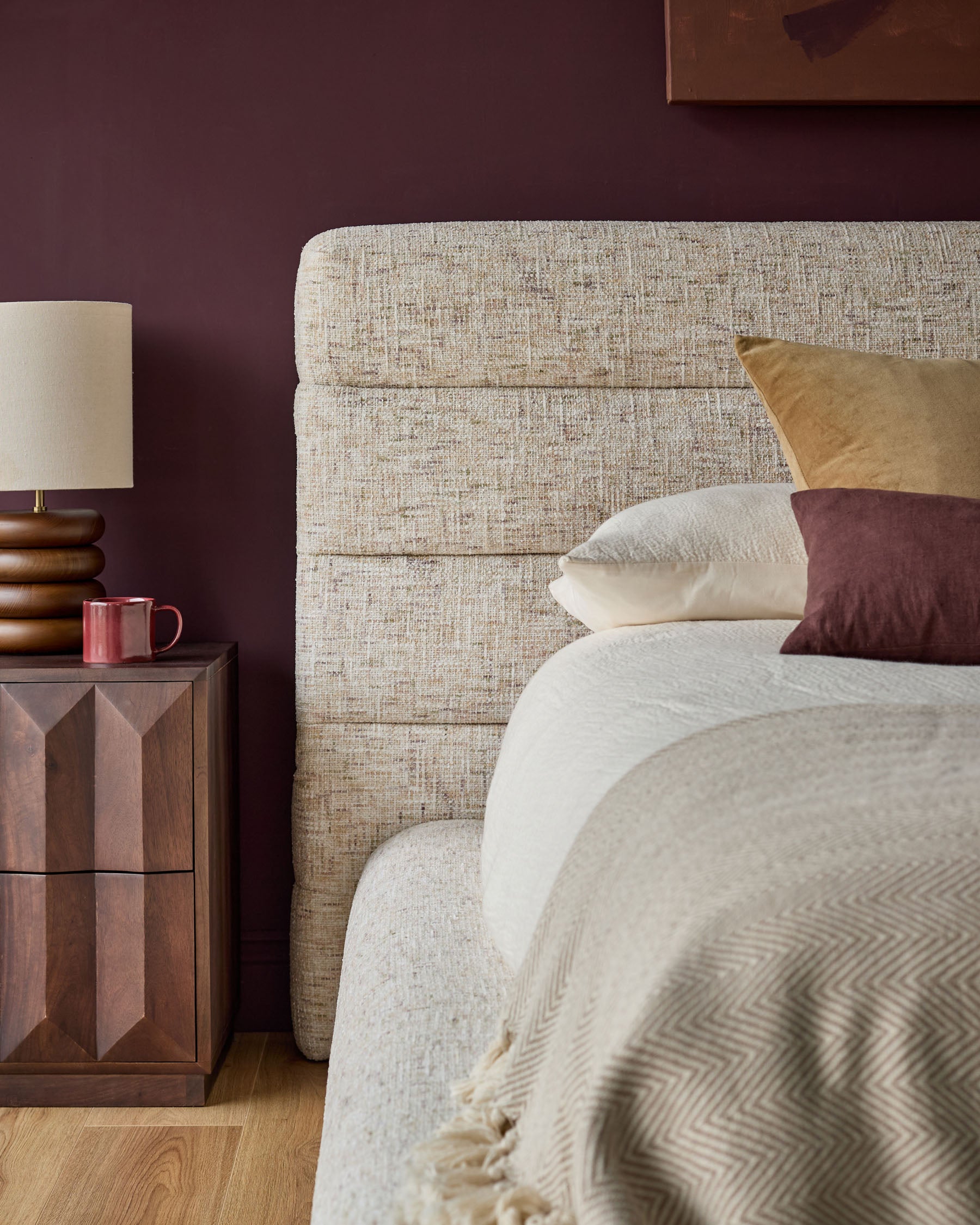 Hepworth king-size ottoman bed with natural linen upholstery, displayed in bedroom setting with neutral bedding and burgundy accent wall.