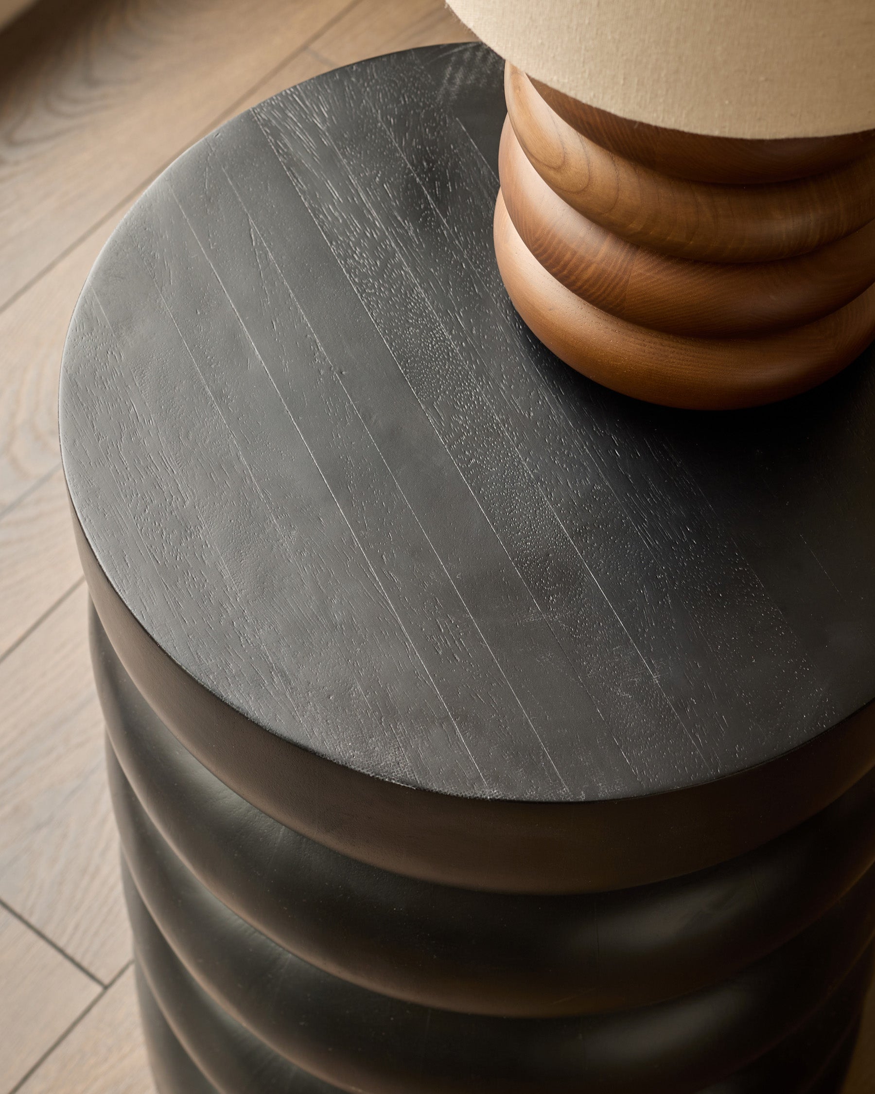 Hepworth side table in black mango wood, showing round tabletop with wood grain texture and curved wooden base.