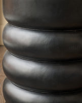 Close-up of stacked black mango wood sections showing curved, bulbous design and smooth finish of side table.