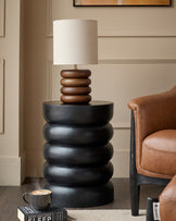 Black stacked side table with mango wood lamp base in contemporary living room setting.