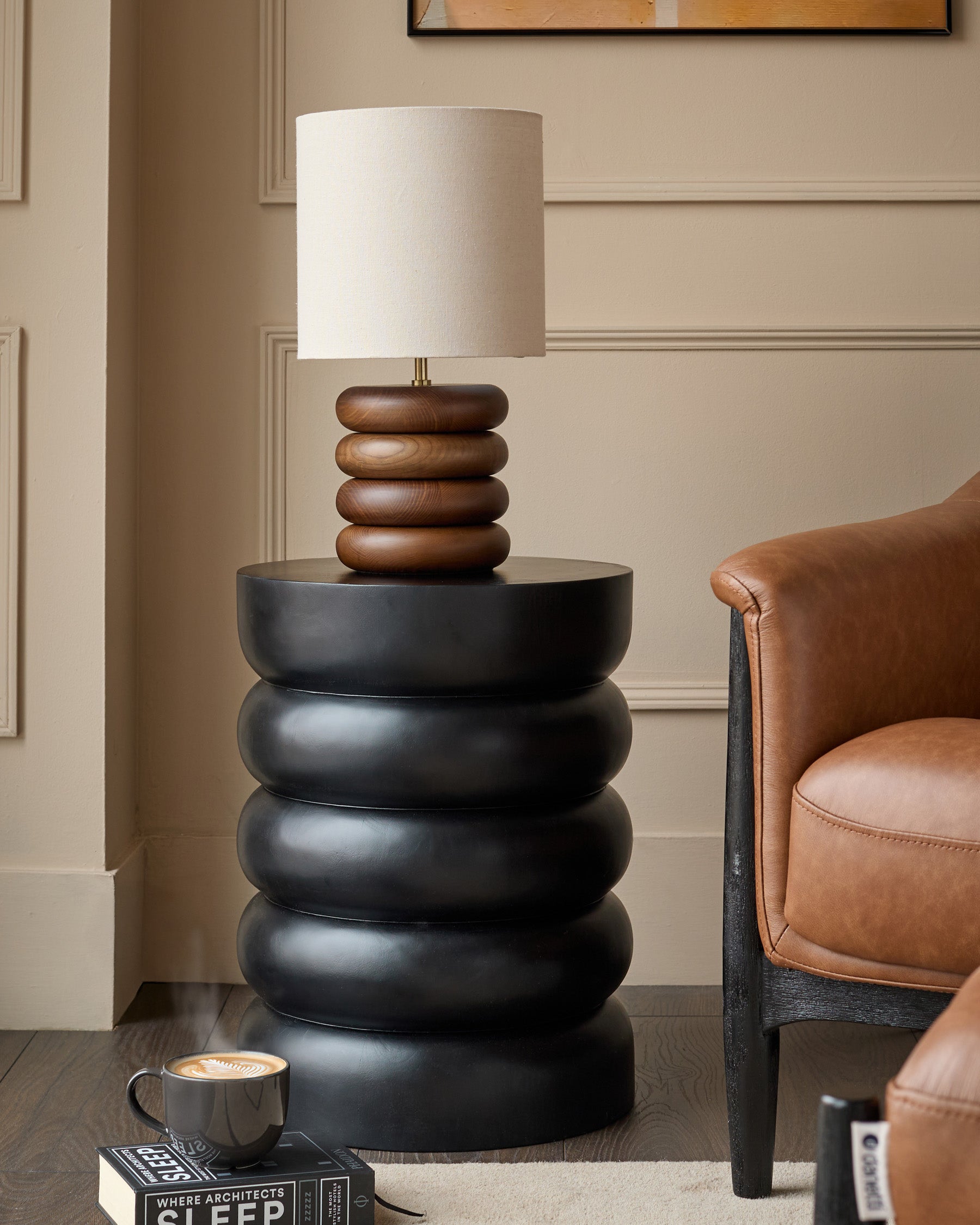 Black stacked side table with mango wood lamp base in contemporary living room setting.