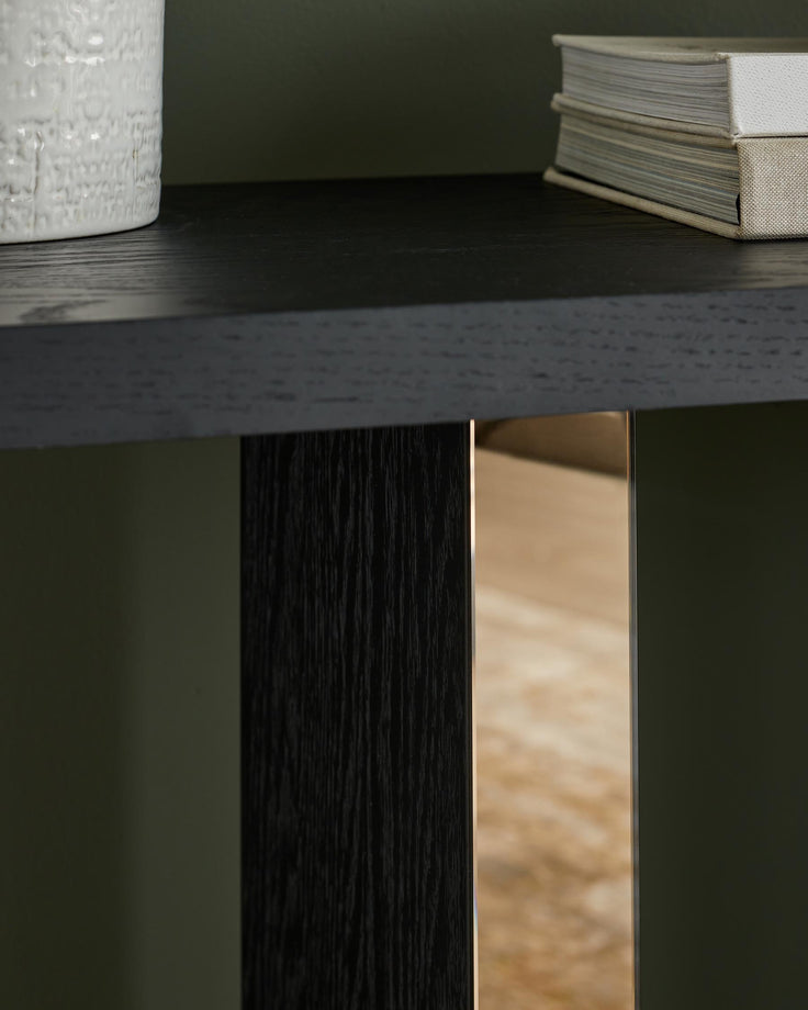 Close-up of a dark wood table with a vase, books and a metallic detail. Modern design.