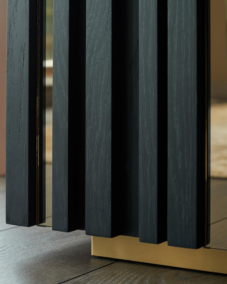 Close-up of a black, ribbed cabinet with gold accents, showcasing its elegant design and textured wood grain.