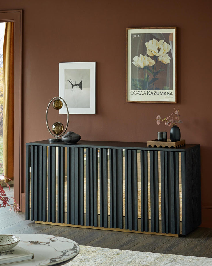 A black sideboard with gold accents and decorative items, under framed artwork, creates a stylish interior focal point.