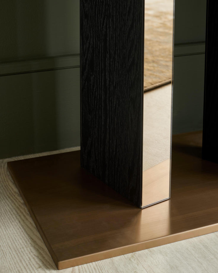 A modern table with a bronze base and dark wood legs, with a mirrored centre piece. Contemporary furniture design.