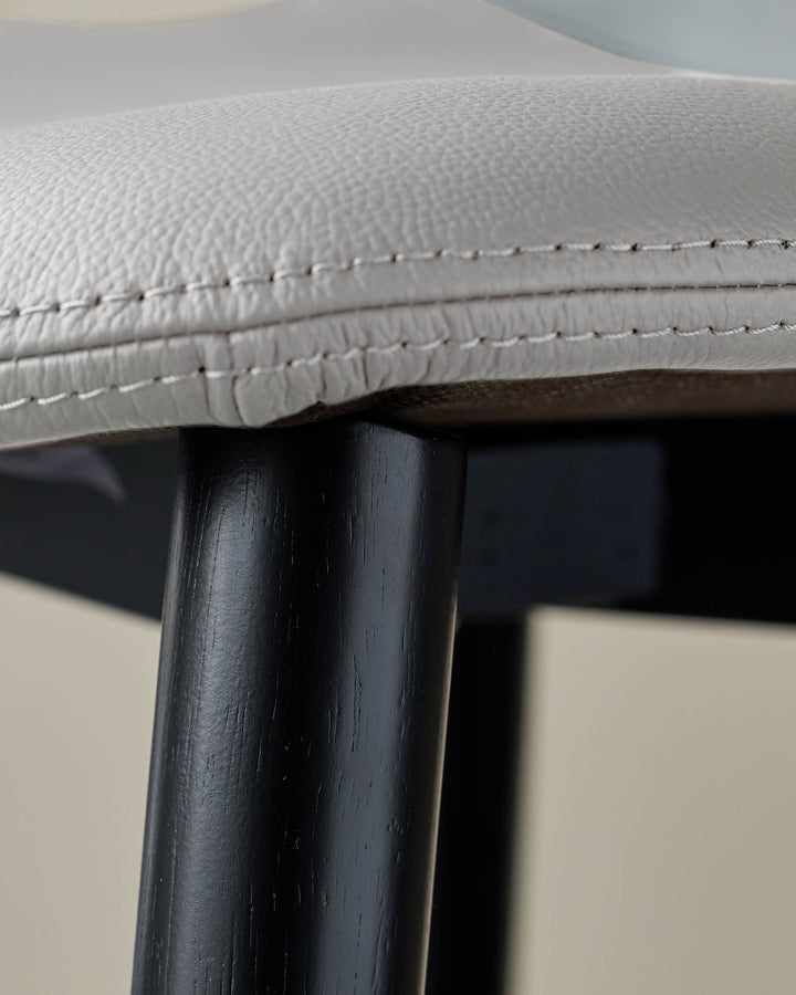 Close-up of a stylish stool with a black leg and light grey seat. Classic design and neutral colours.