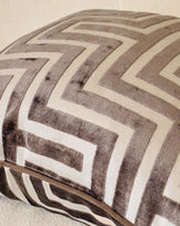 Chocolate brown and cream chevron patterned cushion with piping detail, angled close-up view.