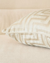 Imani cushion in ivory with tan and cream striped pattern, displayed at an angle on a neutral beige surface.