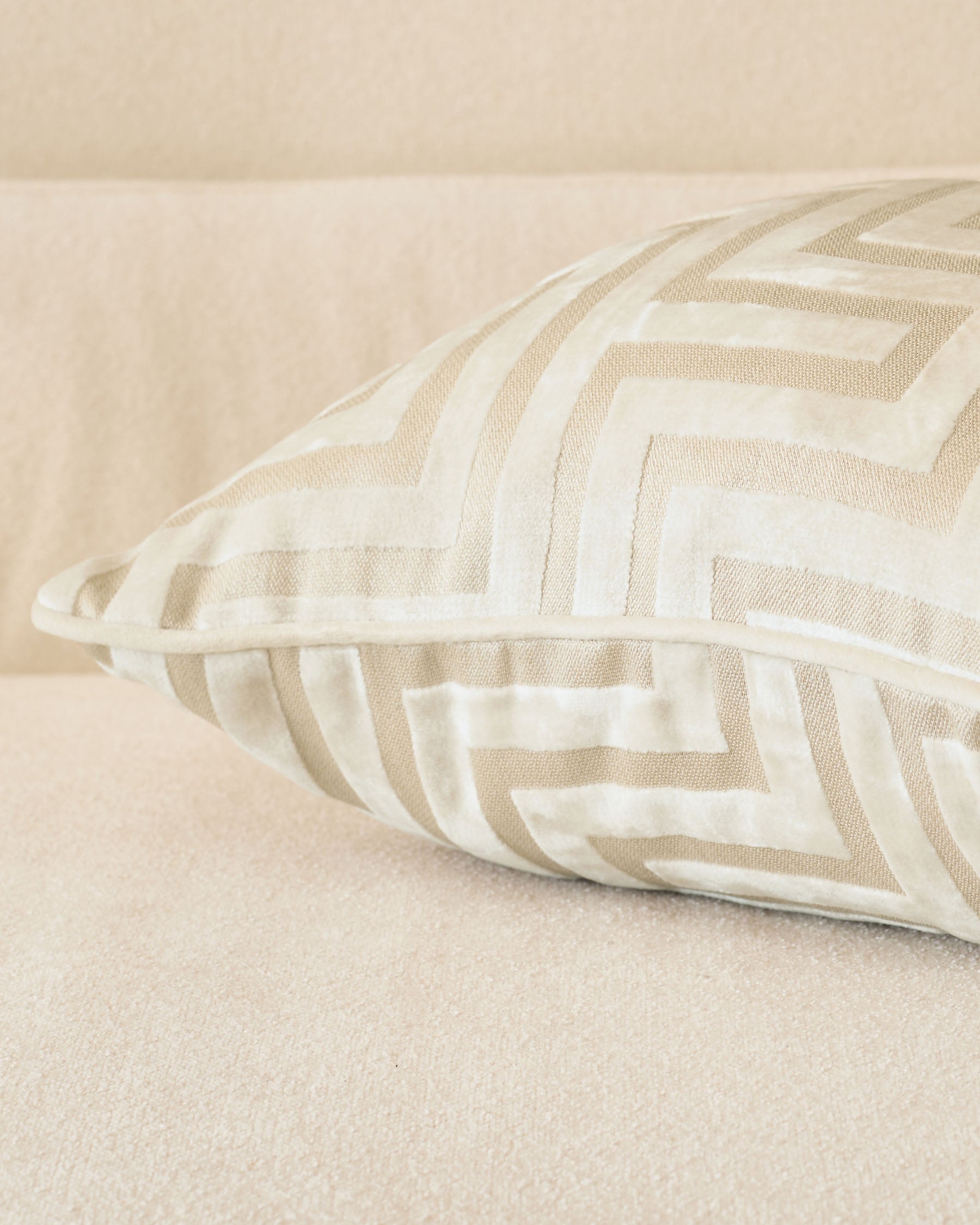 Imani cushion in ivory with tan and cream striped pattern, displayed at an angle on a neutral beige surface.