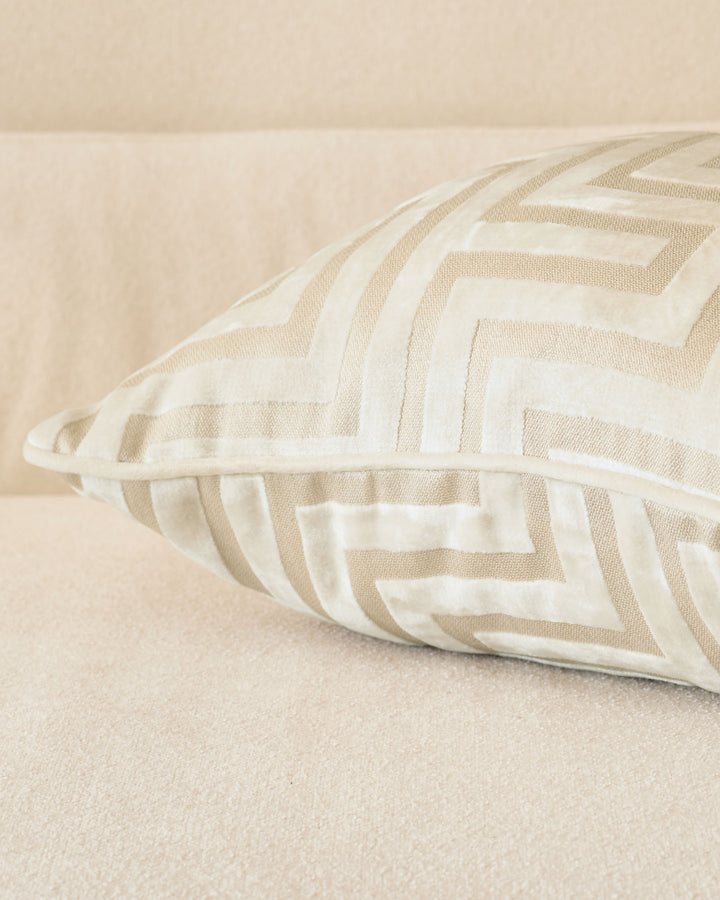 Imani cushion in ivory with tan and cream striped pattern, displayed at an angle on a neutral beige surface.
