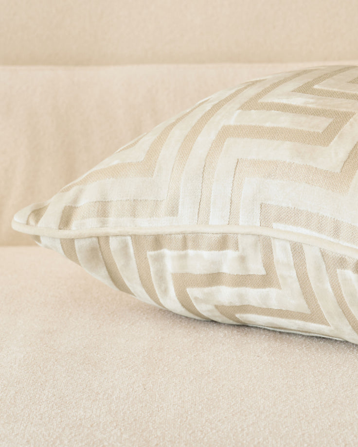 Imani cushion in ivory with tan and cream striped pattern, displayed at an angle on a neutral beige surface.