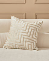 Imani cushion in ivory with geometric tan and cream striped pattern, displayed on a beige upholstered sofa.