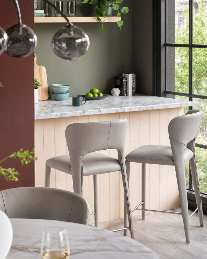 Jackson bar stool in light grey real leather, shown in kitchen setting at marble countertop with footrest detail visible.