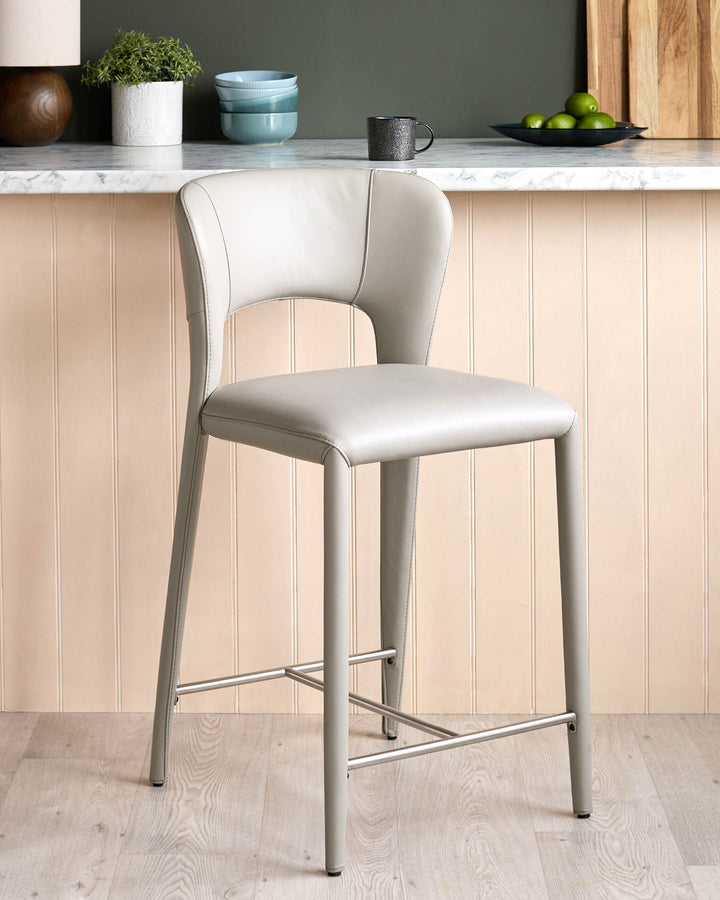 Jackson bar stool in light grey real leather with metal footrest, positioned at marble-topped kitchen counter.