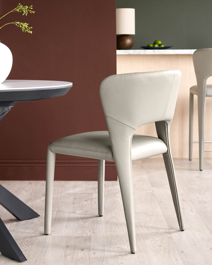 Jackson dining chair in light grey real leather, shown from side angle in modern dining room setting.
