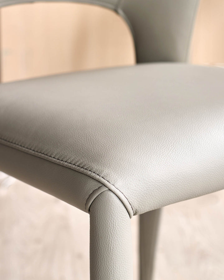 Jackson dining chair in light grey real leather, close-up detail of seat and leg seaming.