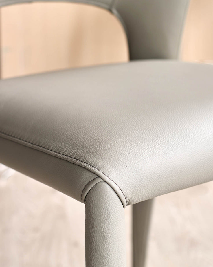 Jackson dining chair in light grey real leather, close-up detail of seat and leg seaming.