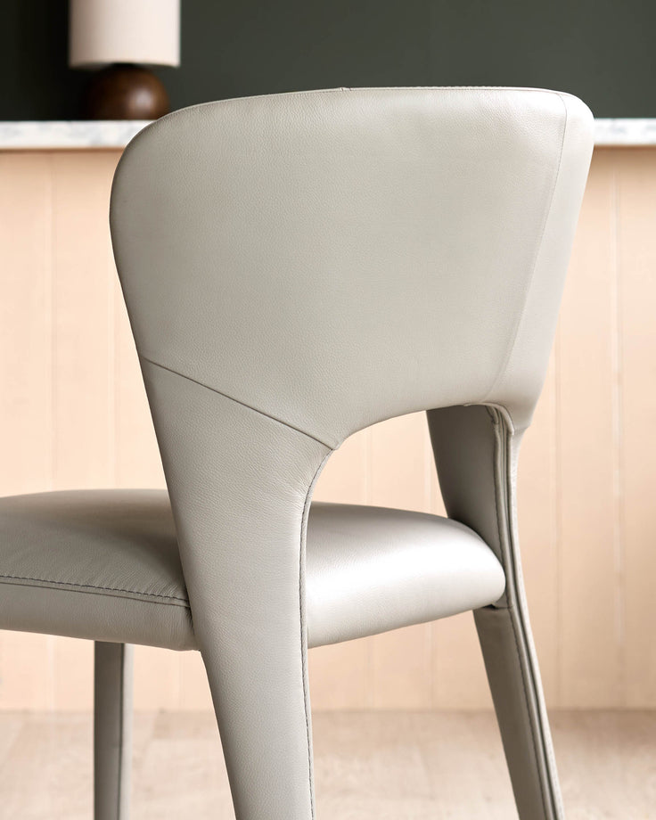Jackson dining chair in light grey real leather, shown from rear angle highlighting curved backrest and seating.