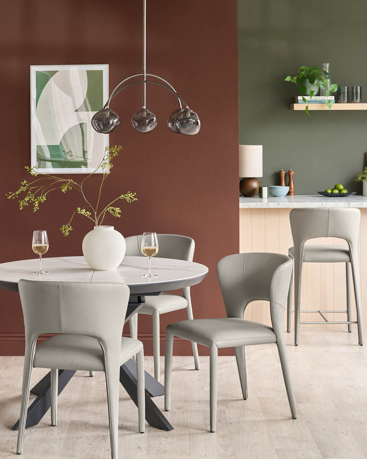 Jackson dining chair in light grey real leather, shown in a dining room setting with round white table and terracotta accent wall.