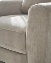 Jacob armchair in light grey fabric, close-up detail of rounded armrest and seat cushion.