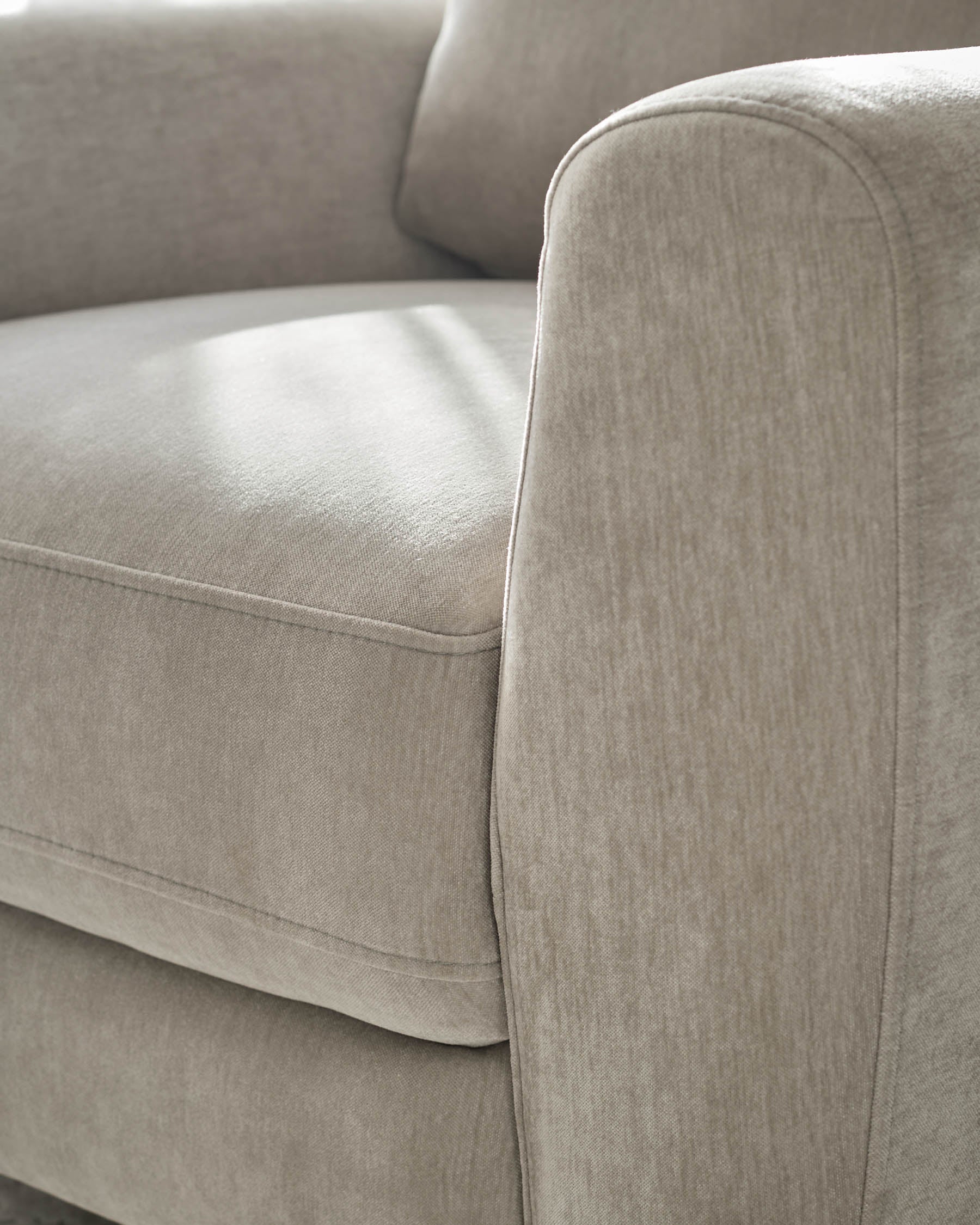 Jacob armchair in light grey fabric, close-up detail of rounded armrest and seat cushion.