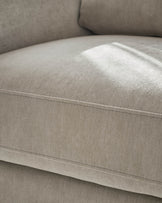 Jacob armchair in light grey fabric, close-up of seat and backrest showing seam detail and cushioning.