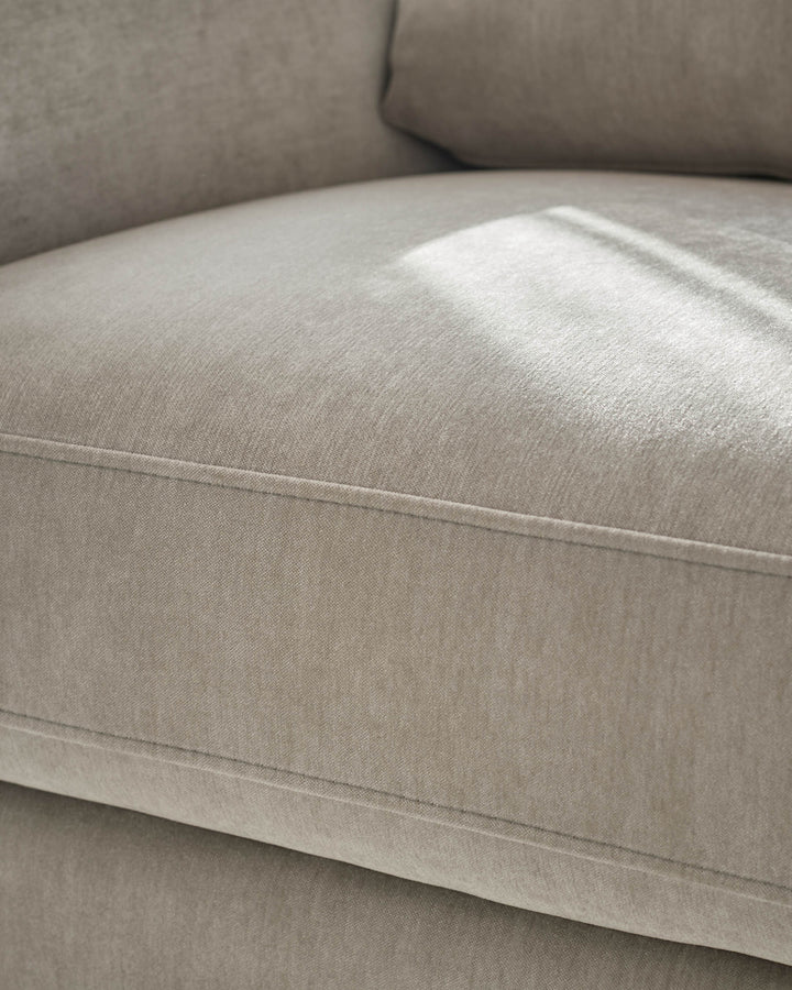 Jacob armchair in light grey fabric, close-up of seat and backrest showing seam detail and cushioning.
