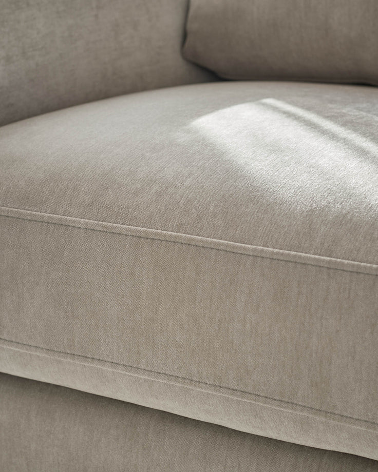 Jacob armchair in light grey fabric, close-up of seat and backrest showing seam detail and cushioning.