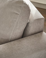 Jacob armchair in light grey fabric, detail view showing cushioned seat and curved armrest design.