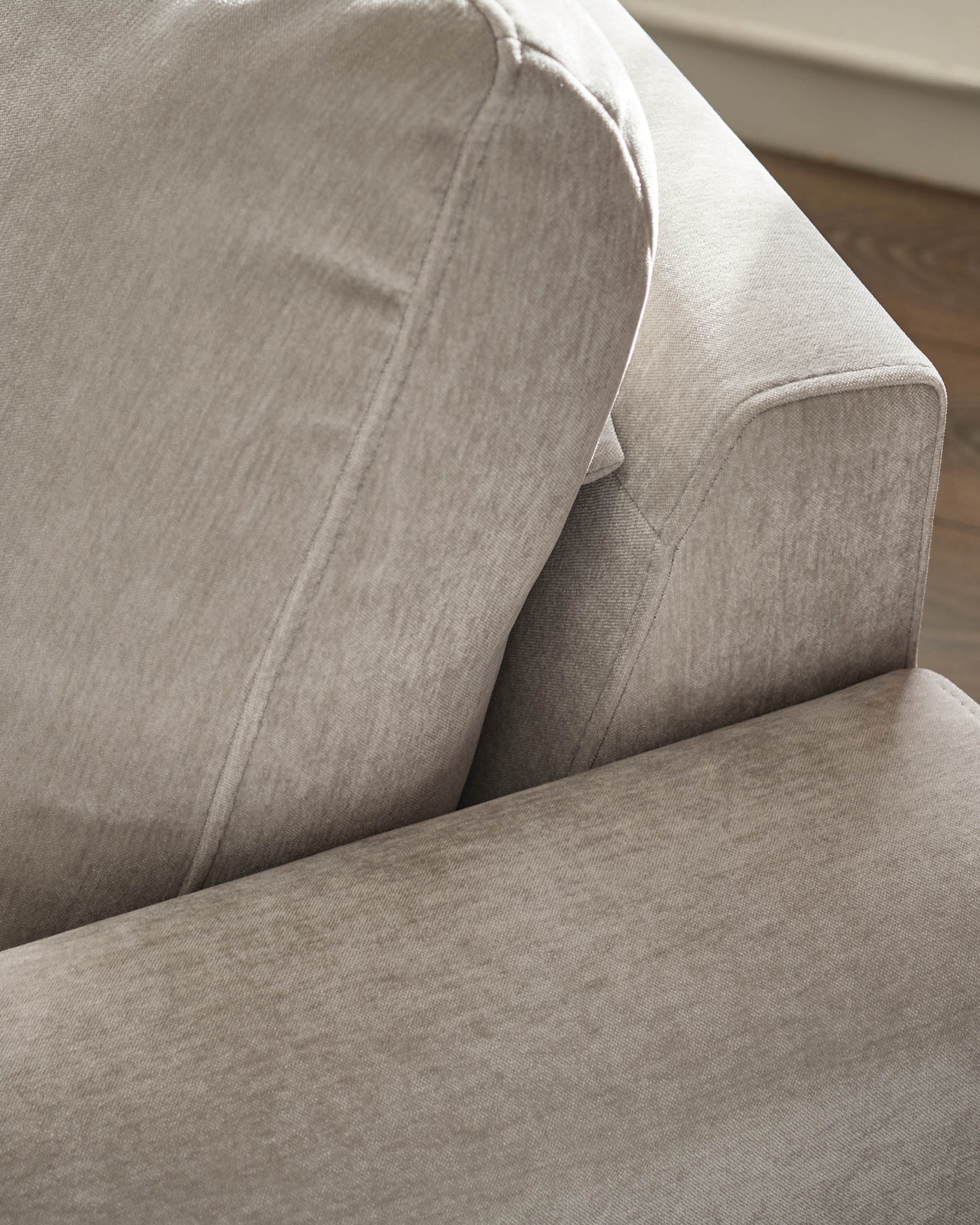 Jacob armchair in light grey fabric, detail view showing cushioned seat and curved armrest design.