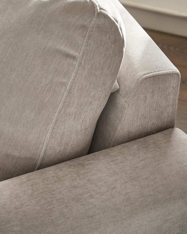Jacob armchair in light grey fabric, detail view showing cushioned seat and curved armrest design.