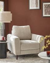 Jacob armchair in light grey fabric with rolled arms and dark wooden legs, positioned in a styled living room setting.