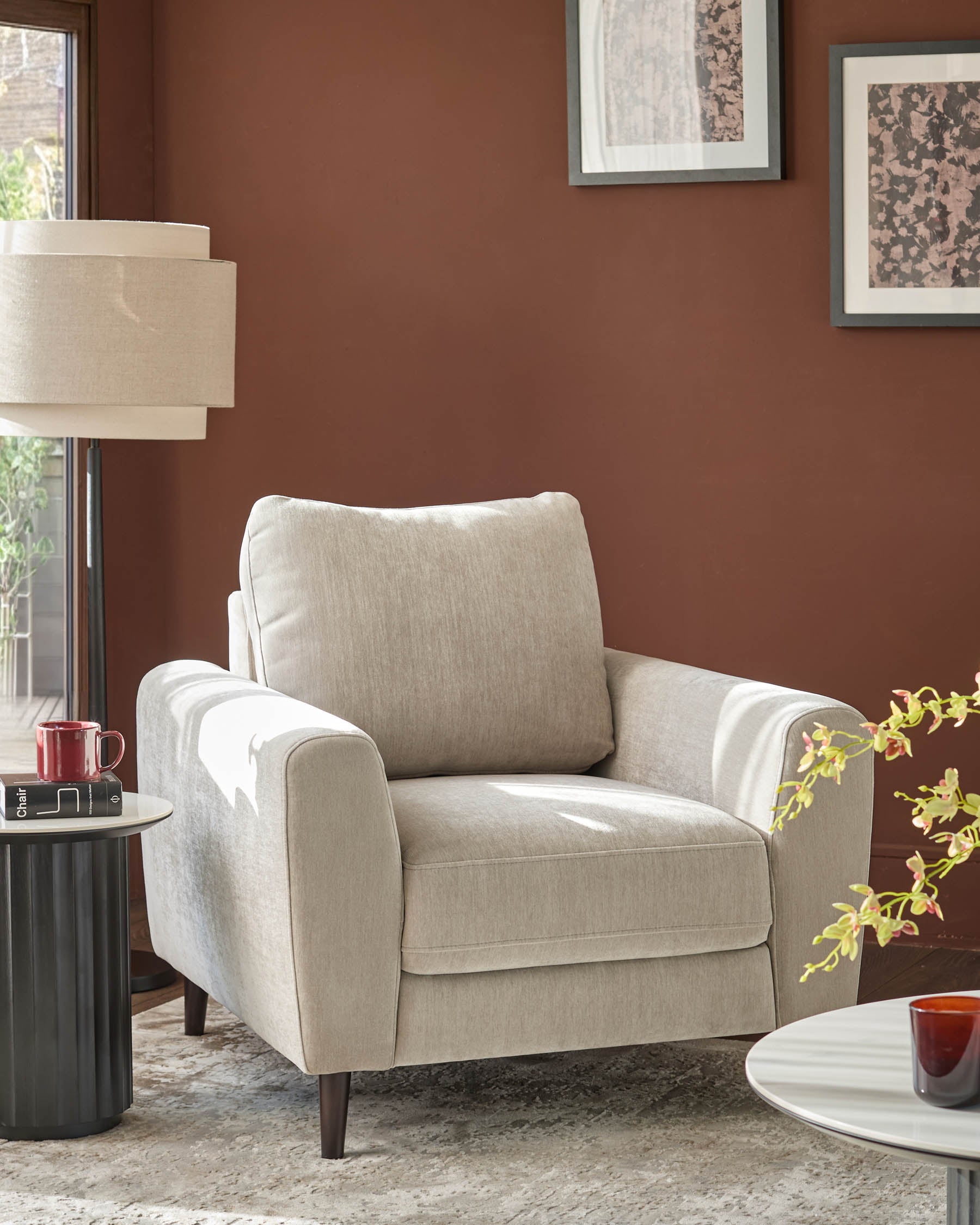 Jacob armchair in light grey fabric with rolled arms and dark wooden legs, positioned in a styled living room setting.