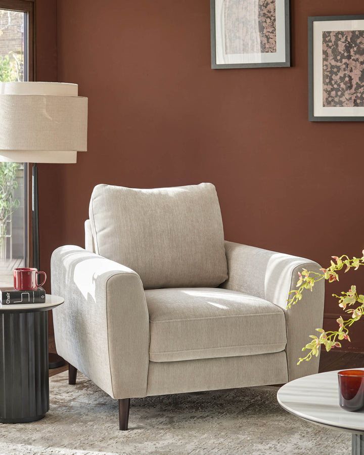 Jacob armchair in light grey fabric with rolled arms and dark wooden legs, positioned in a styled living room setting.