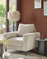 Light grey fabric armchair with rolled arms, back pillow, and dark wooden legs in a styled living room setting.