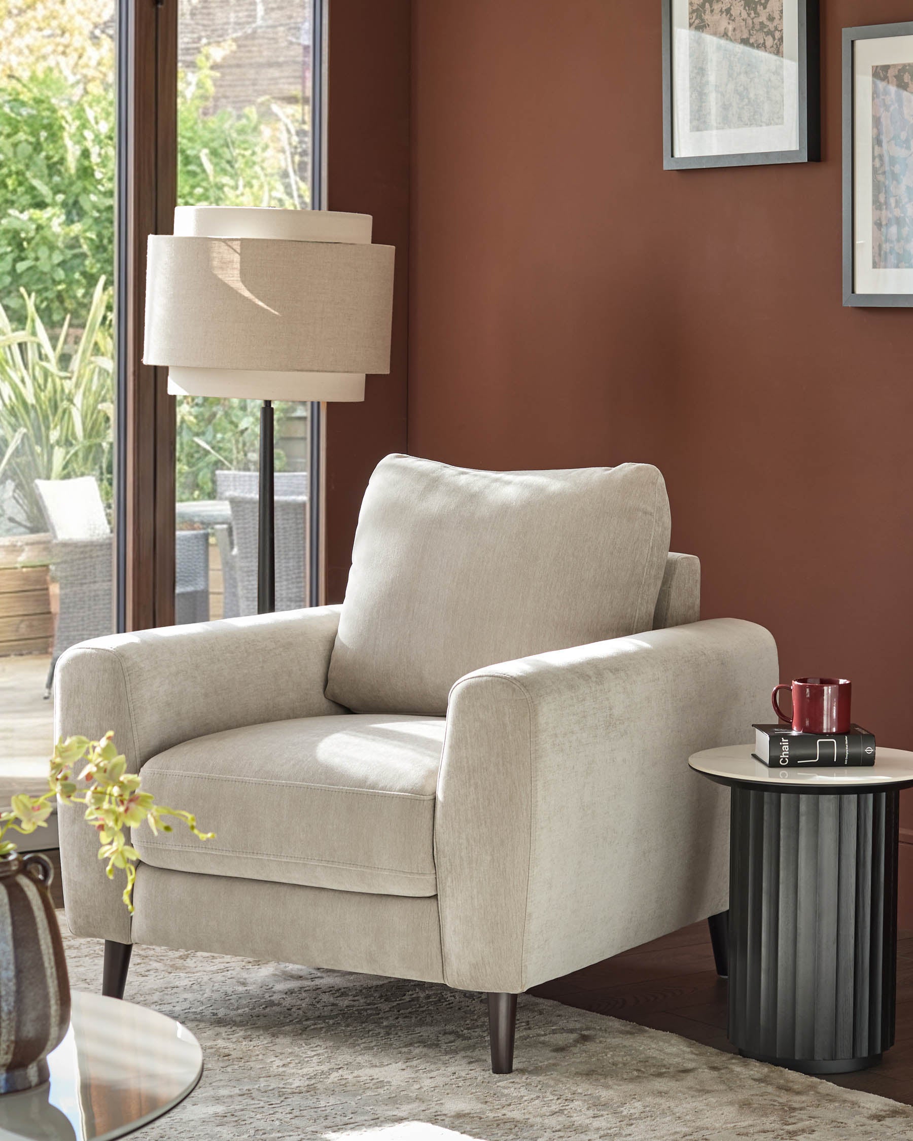 Light grey fabric armchair with rolled arms, back pillow, and dark wooden legs in a styled living room setting.