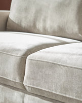 Light grey fabric 3-seater sofa with white piping detail and plush cushions, close-up side view.