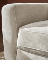 Close-up of light grey fabric sofa armrest and seat cushion with white topstitching detail.