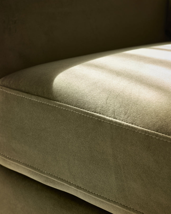Jacob armchair in olive-green velvet, close-up side view showing plush upholstery and stitched seam detail.