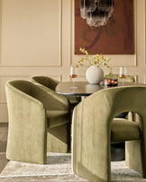 Jasper dining chair in olive green velvet, shown in a styled dining setting around a round table with coordinating chairs.