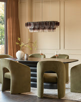 Olive green velvet dining chair with curved sculptural silhouette in modern dining room setting.