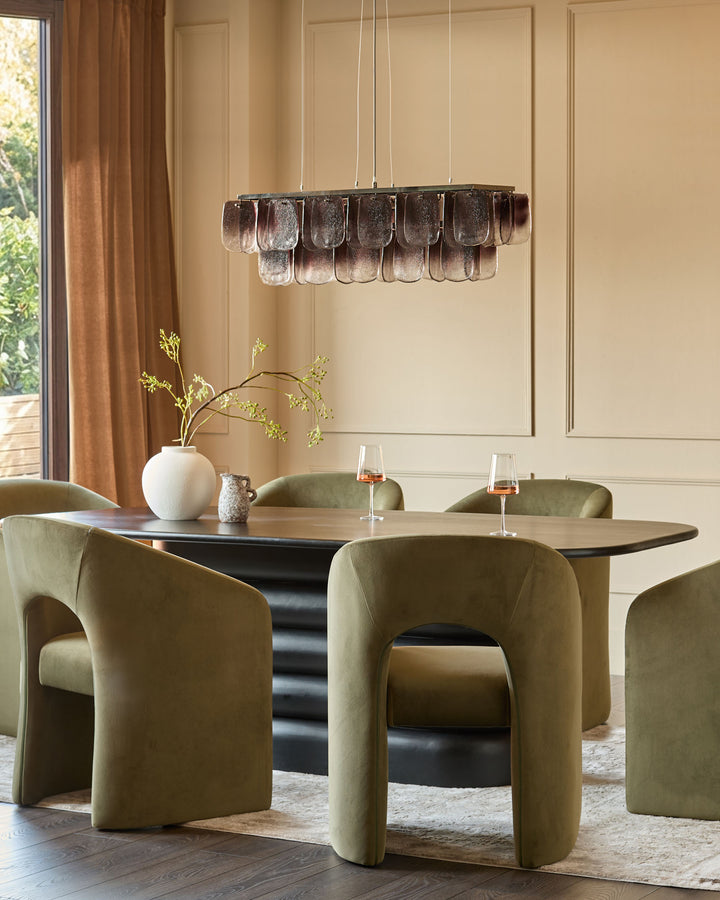 Olive green velvet dining chair with curved sculptural silhouette in modern dining room setting.