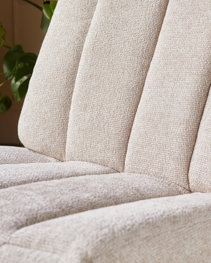 Close-up of a cream coloured chair with textured fabric. The seat and back have vertical stitched detailing.