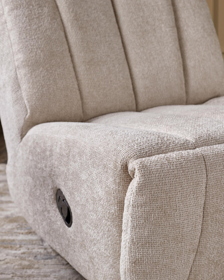Close-up of an upholstered recliner armchair in a neutral colour, featuring a reclining lever.