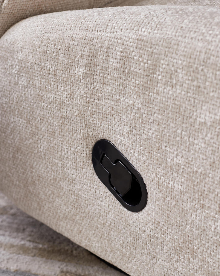 Close up of a beige upholstered recliner with black handle on a sofa.