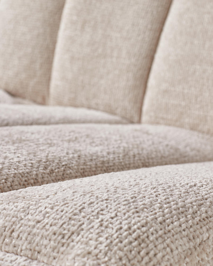 Close-up of a cream sofa, showing the textured fabric and soft cushioning.