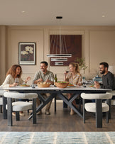 Jennet extending dining table in white ceramic with black X-frame base, seated by four people during a dinner gathering.